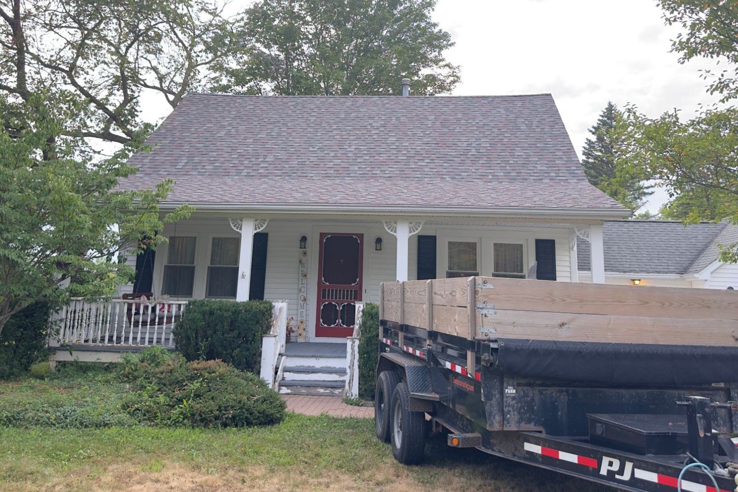 Completed shingle roof on a white farmhouse with a covered porch
