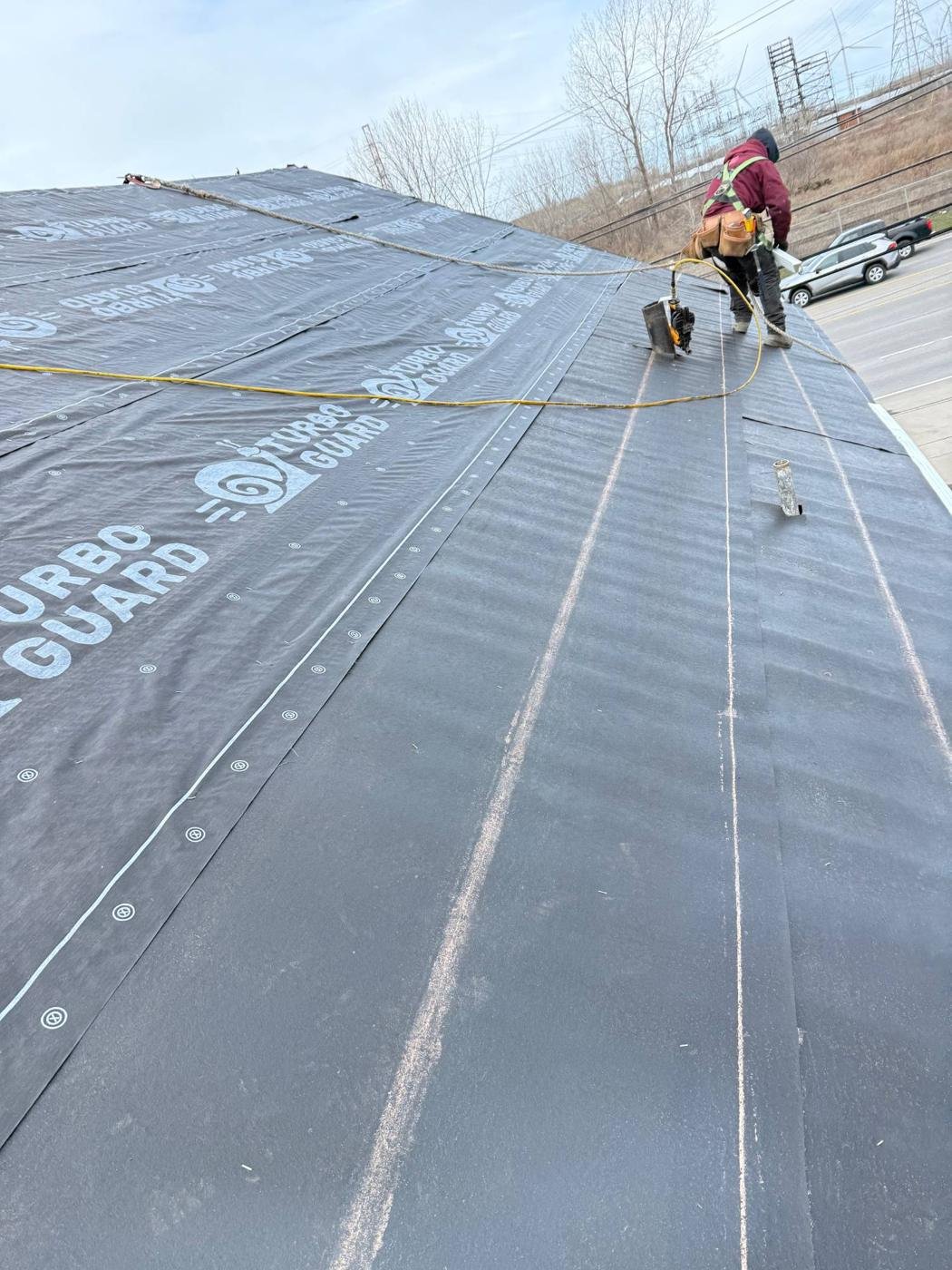 Roofer installing synthetic underlayment