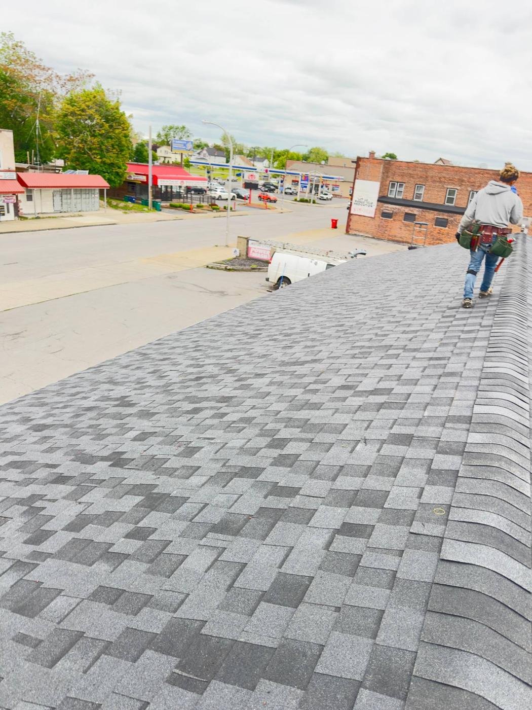 Roofer checking shingles along a roof ridge